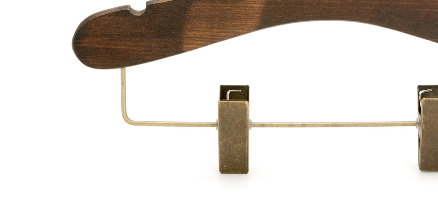 Close-up image of a Hangers of London Wooden Antique Kids Top Clip (Brass Hook) 28cm made from dark ash wood with metal clips. The hanger features a dark brown finish and a curved design at the top, with metal clasps attached to the bottom for securing garments. The background is plain and white.