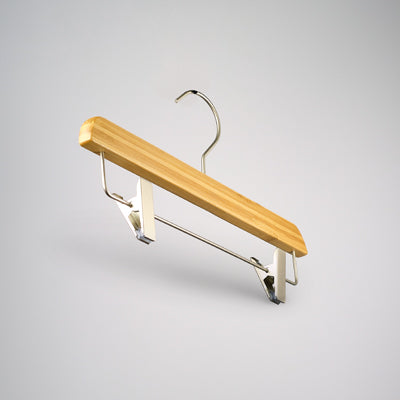 A Bamboo Wood Sustainable Clip Bottom Hanger 35cm by Hangers of London with a metal hook and adjustable clips for securing clothing. The hanger is set against a plain gray background, showcasing its simple and functional design as an eco-friendly wardrobe accessory.