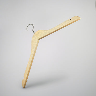 A high-quality wood hanger with a metal hook is suspended against a plain, light grey background. The Hangers of London Natural Wood Top Clothes Hanger with Notch 38cm features a notch on each end and a slight, curved shape.