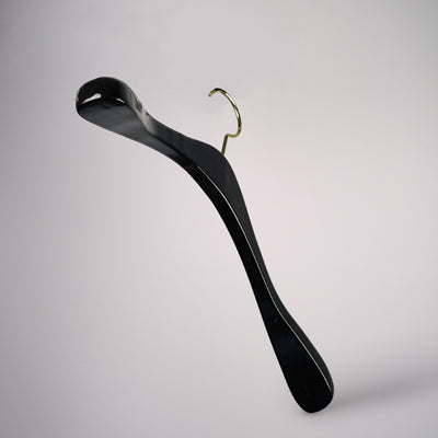 A sleek, modern Black Wooden Top Coat Premium Hanger 42cm from Hangers of London with a metallic hook is set against a plain, light gray background. Crafted from high-quality black wood, the hanger features an elegant curve design and a nonslip grip, blending functionality with a minimalist aesthetic.