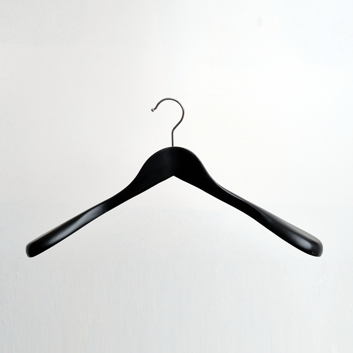 A Hangers of London Black Wooden 45 cm Jacket Hanger from a pack of 24 is displayed centered against a plain white background, featuring a silver hook.