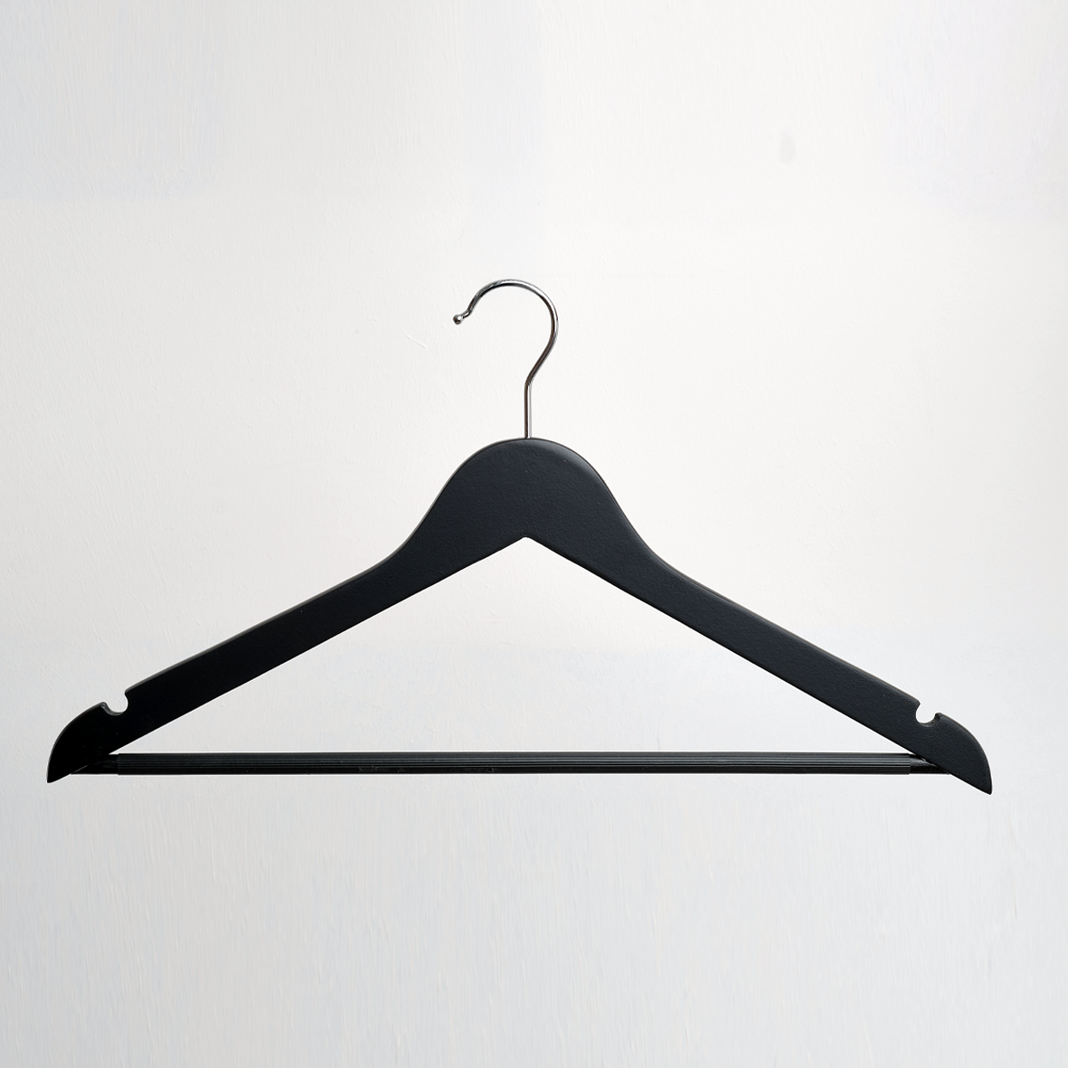 The Hangers of London Black 44cm Wooden Clothes Hanger With Non Slip Trouser Bar, featuring a sleek black finish and a sturdy metal hook, is displayed against a plain white background.