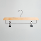 A Hangers of London Natural Wooden 35cm Clip Hanger, featuring sturdy metal clips and a metal hook, is displayed hanging against a plain, light-colored wall.