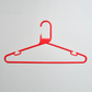 A Heavy Duty Economy Red Multi Purpose Rainbow Hanger by Hangers of London, made of plastic and featuring a hook, is displayed hanging against a plain white wall.
