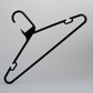 The Hangers of London Heavy Duty Economy Black Multi Purpose Rainbow Hanger is positioned upright against a plain gray background, showcasing its black plastic design with hooks on both sides.
