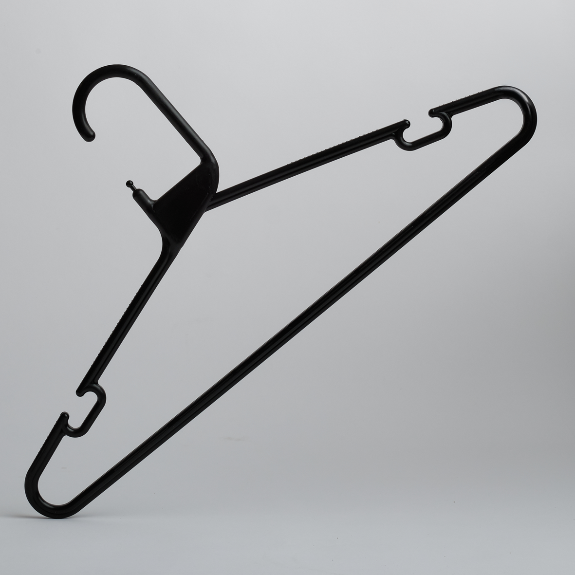The Hangers of London Heavy Duty Economy Black Multi Purpose Rainbow Hanger is positioned upright against a plain gray background, showcasing its black plastic design with hooks on both sides.
