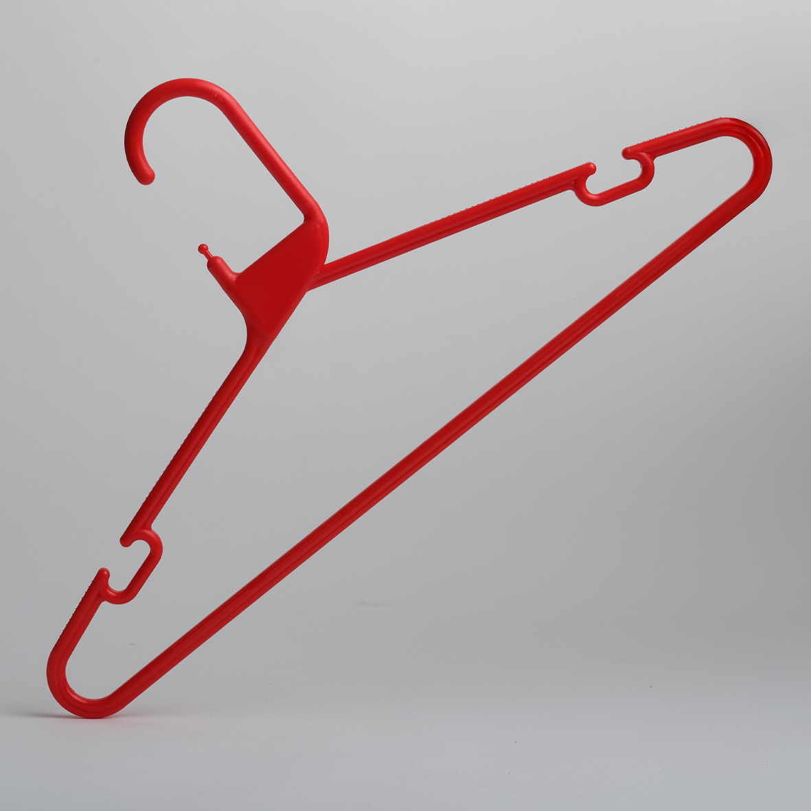 The Heavy Duty Economy Red Multi Purpose Rainbow Hanger by Hangers of London is displayed against a plain light gray background, showcasing its distinctive angular red plastic design.