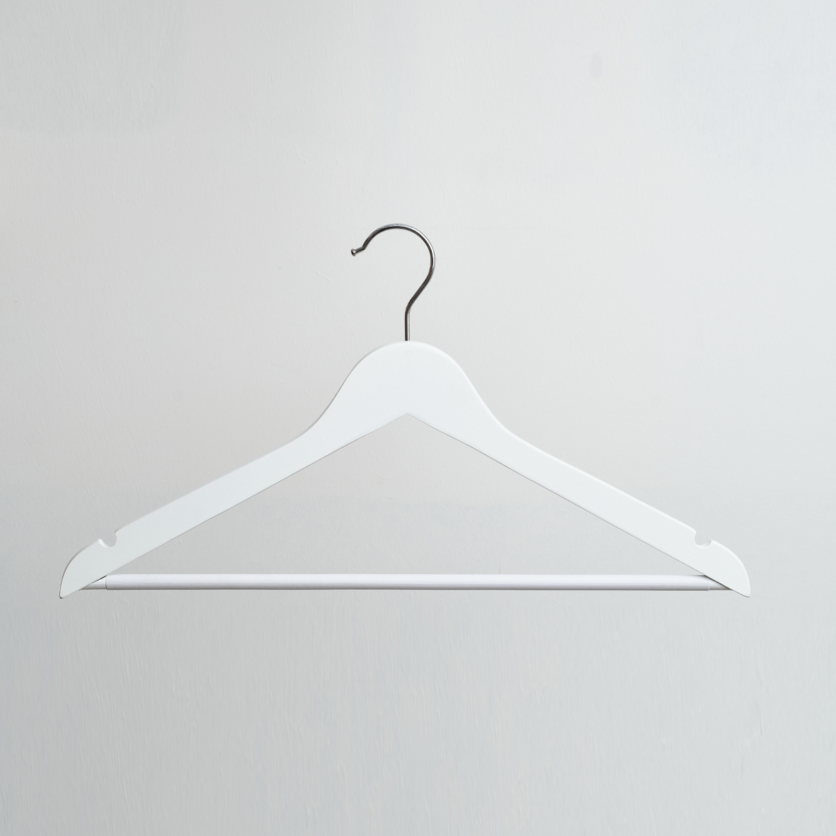 A White Wooden 44cm Top Hanger With Non Slip Trouser Bar by Hangers of London is hanging against a plain light gray background.