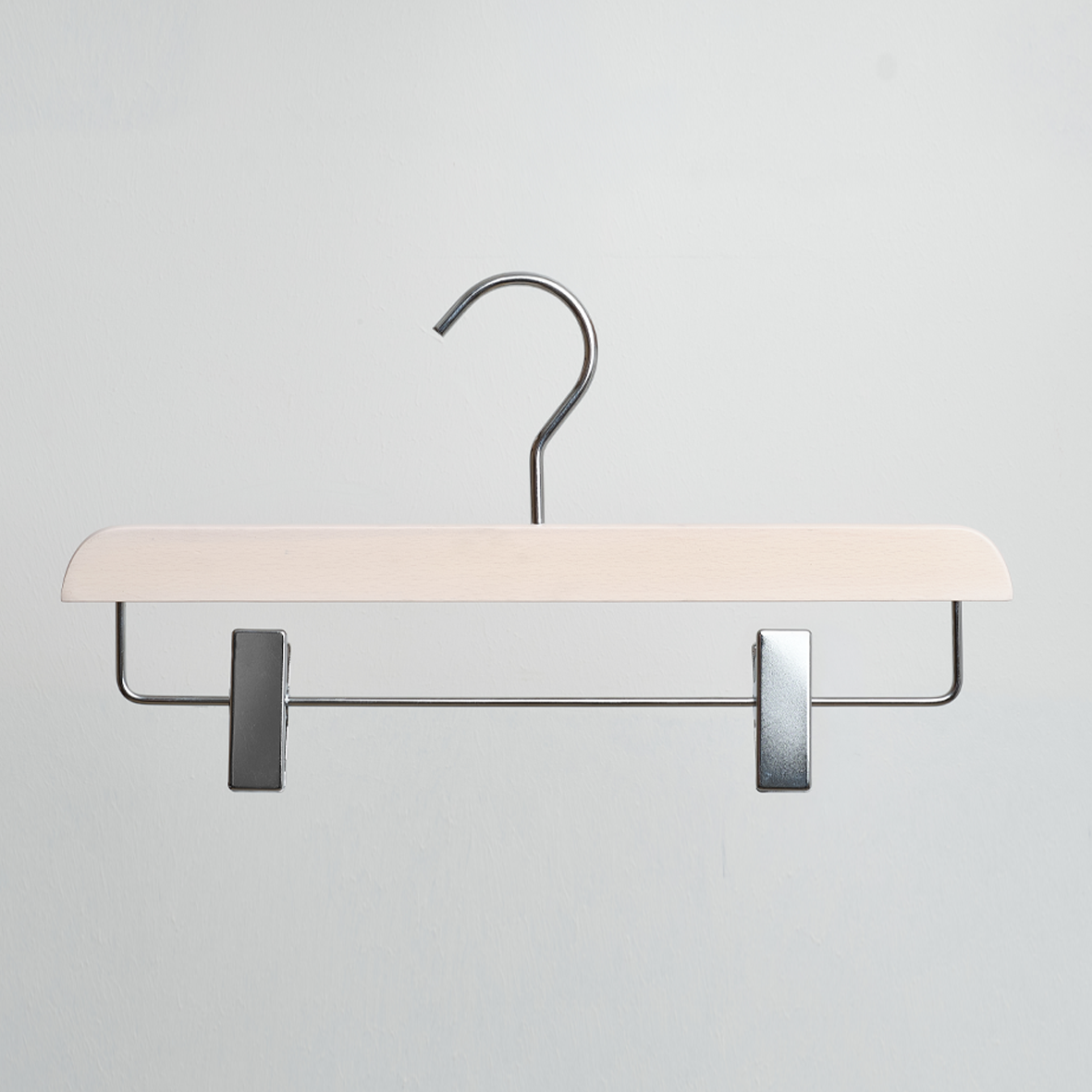 A Hangers of London Luxury Whitewash FSC Certified Beech Wooden 35cm Clip Hanger, featuring two adjustable metal clips, hangs against a plain light gray background.