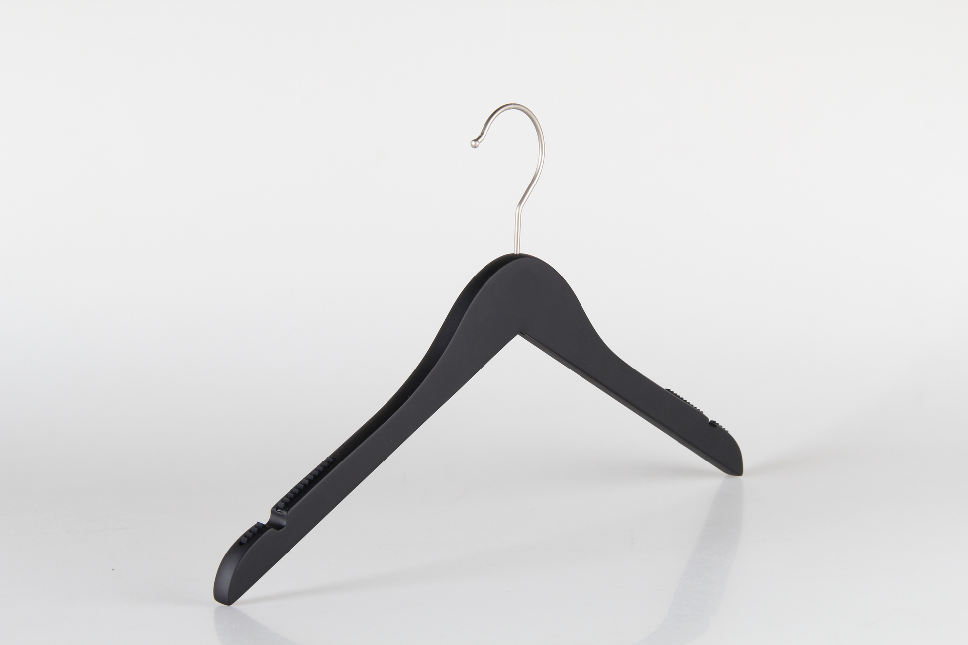 A Hangers of London Wooden Rubber Soft Touch Black Kids Top (30cm) with a shiny silver hook is positioned against a plain white background. The hanger features indents on the shoulders for securing garments with straps. The simple design and reflective surface create a minimalistic and modern appearance, ideal for children's clothes.